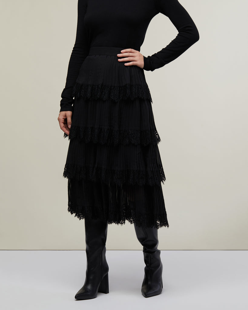 Close up image of model in photo studio posing with hand on hip wearing Black Tiered Pleated Skirt with Lace Trim