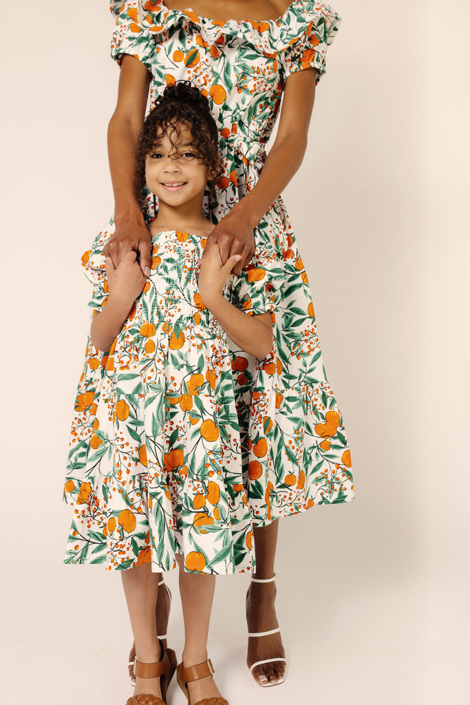 Mommy & Mini Models Kayt and Tay in Orange Blossom Sky Printed Off Shoulder Midi Dress and Girls Orange Blossom Puff Sleeve Dress