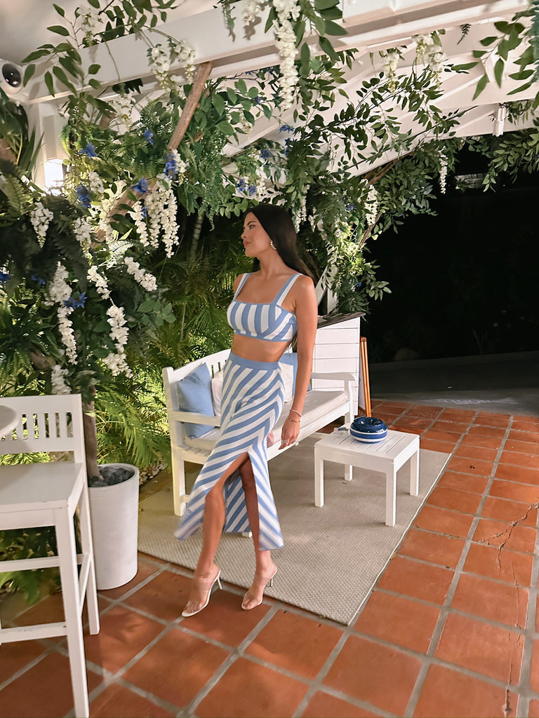 Rachel Parcell standing outside restaurant in St. Barths wearing blue and white striped skirt and top set