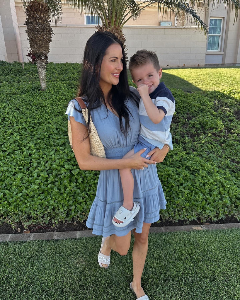 Rachel Parcell holding son, Ford outside church in Hawaii wearing Open Back Smocked Mini Dress in Ice Water Blue