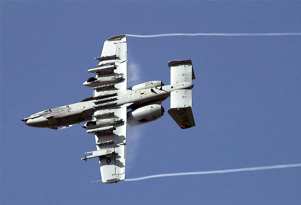 An A-10 rolls to mark a target with simulated M-156 white phosphorus rockets as part of an aerial demonstration.