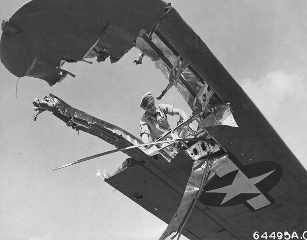 A crew member examines the wing of a Consolidated B-24 Liberator which was damaged during a pre-invasion raid over Iwo Jima during World War II.