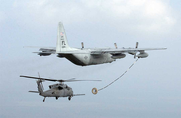 A C-130 conducts an in-flight refueling of a rescue helicopter, allowing the helicopter to continue its search and rescue mission.