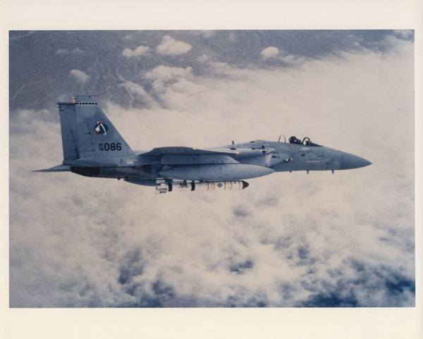 An air-to-air side view of an F-15 Eagle aircraft carrying an anti-satellite (ASAT) missile on it’s centerline station.