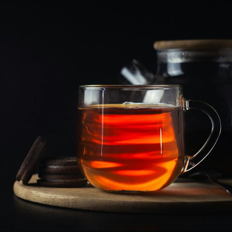 A transparent cup filled with black tea.