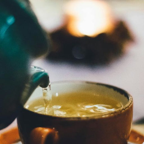 A cup of green tea being poured.