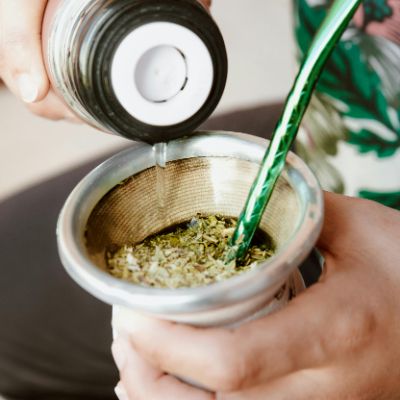 Pouring warm water in a gourd filled with Yerba Mate.