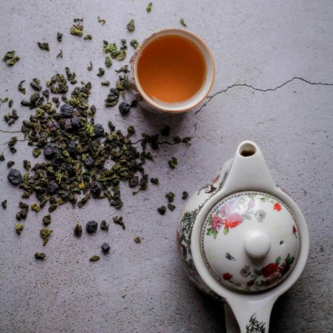 A cup of oolong tea besides a kettle.