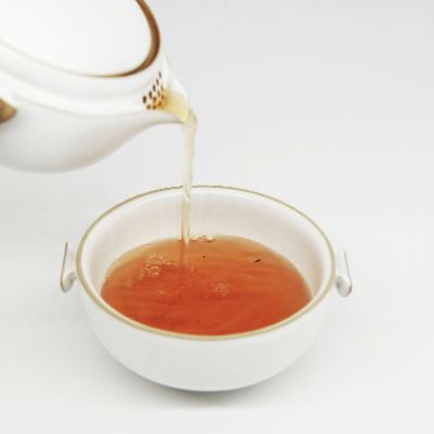 Tea being poured through a teapot into a tea bowl.