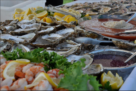 Southold Fish Market the image showing a bountiful seafood display featuring fresh oysters on the half shell, plump shrimp, and a variety of dipping sauces, including cocktail sauce and hot sauce.