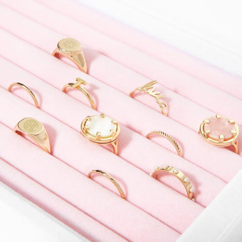 Close up: an assortment of cocktail rings are nestled into a pink jewelry display case