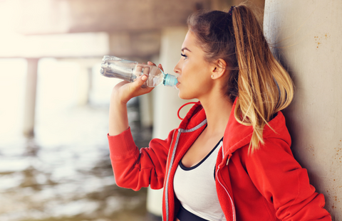 girl drinking water against wall