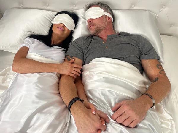 Couple Lying on Ivory Silk Sheets Wearing Ivory Sleep Masks