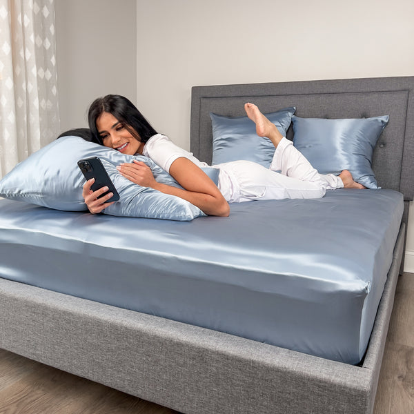 Model Lying on her stomach on Steel Blue Fitted Sheet Using Cellphone