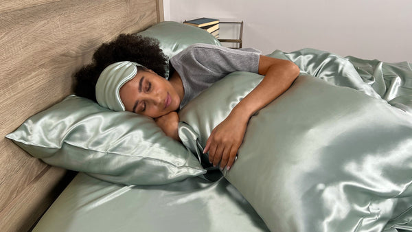 Model Sleeps on sage silk sheets with matching sleep mask