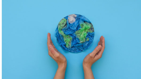 earth day image of hands holding a tissue paper image of earth on a blue background