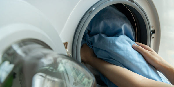 Open washing machine with blue silk sheets inside