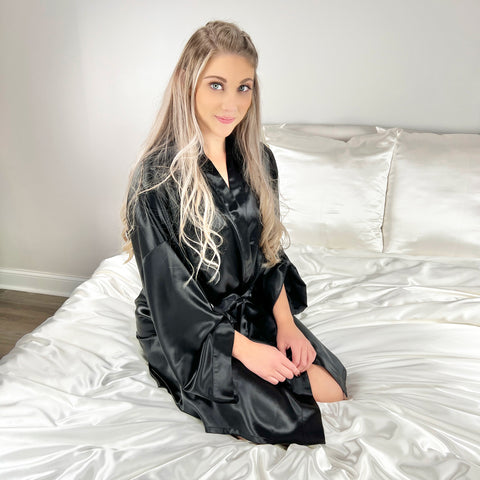 Blonde woman on bed wearing black silk robe.