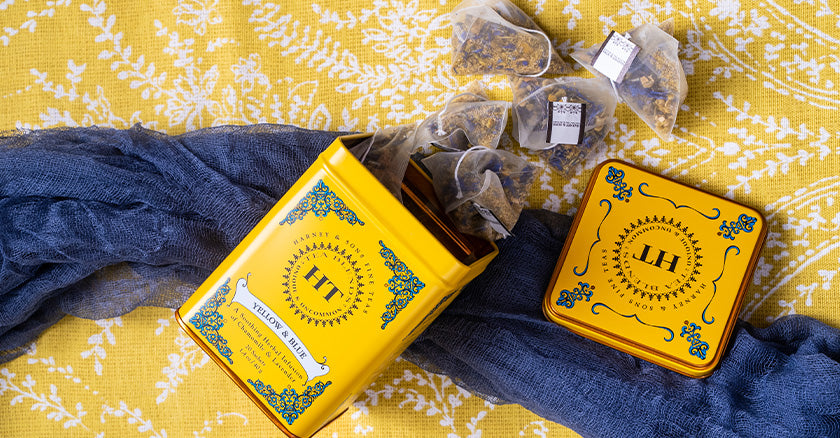 Yellow & Blue herbal tea infusions tin open with several sachets of herbal tea falling out