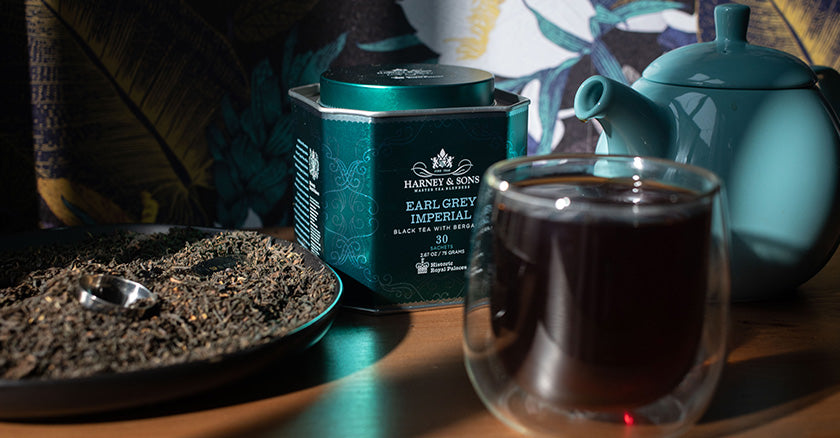 Earl Grey Imperial tin from Harney & Sons surrounded by a large bowl of Earl Grey tea, a brewed cuppa Earl Grey and a turquoise-colored teapot.