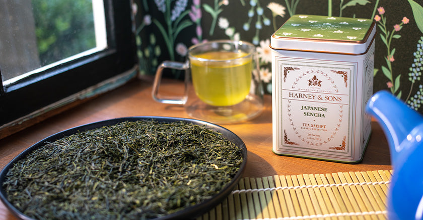 A table with a large bowl of Japanese green tea and behind that to the right a tea tin of Japanese Sencha by Harney & Sons fine tea importers