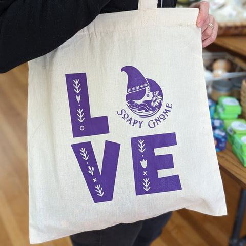 Soapy Gnome tote with purple writing says love with the gnome logo as the O