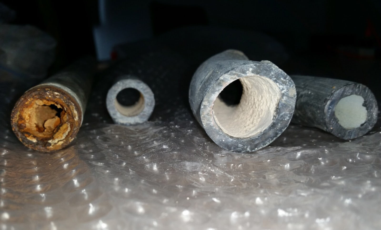 Drinking water pipes without corrosion inhibitor (far left) and with corrosion inhibitor (three remaining pipes with white coating).