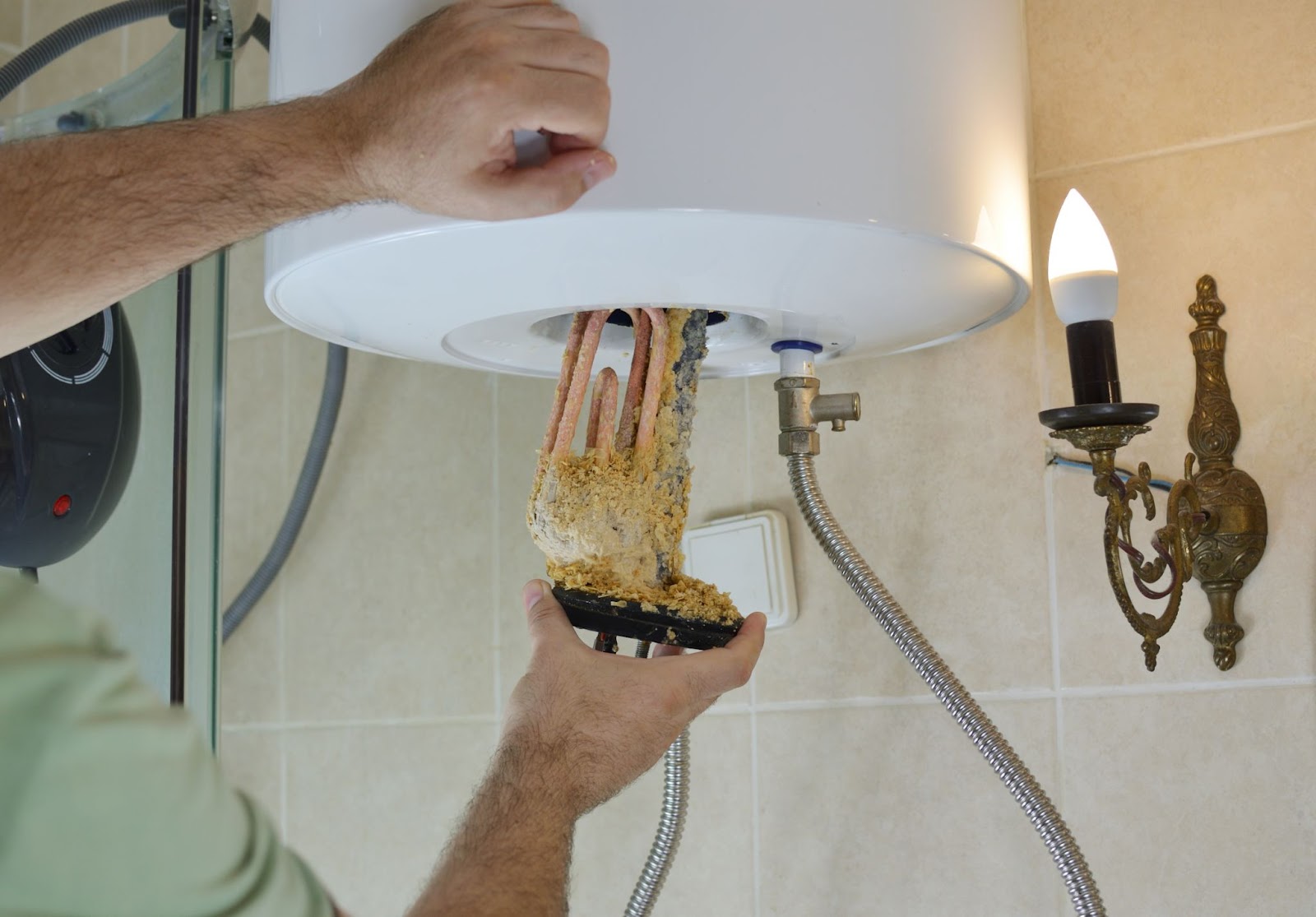 The heating element of a water heater being replaced after excessive scale buildup rendered it nonfunctional.