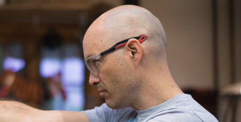 Zack Worrell, knifemaker and founder of Monolith Studio, checks for straightness of a knife blade.