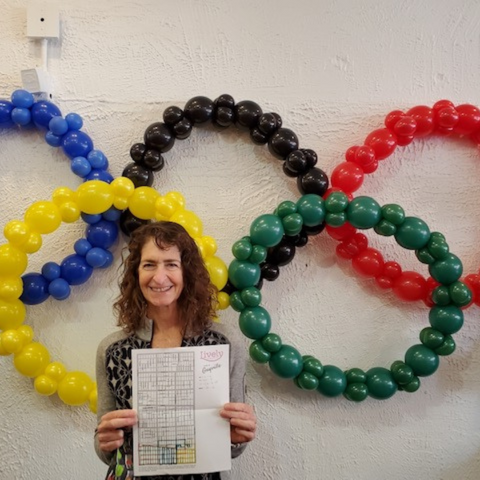 female runner holding a map of oak park in front of balloons shaped like the olympics logo