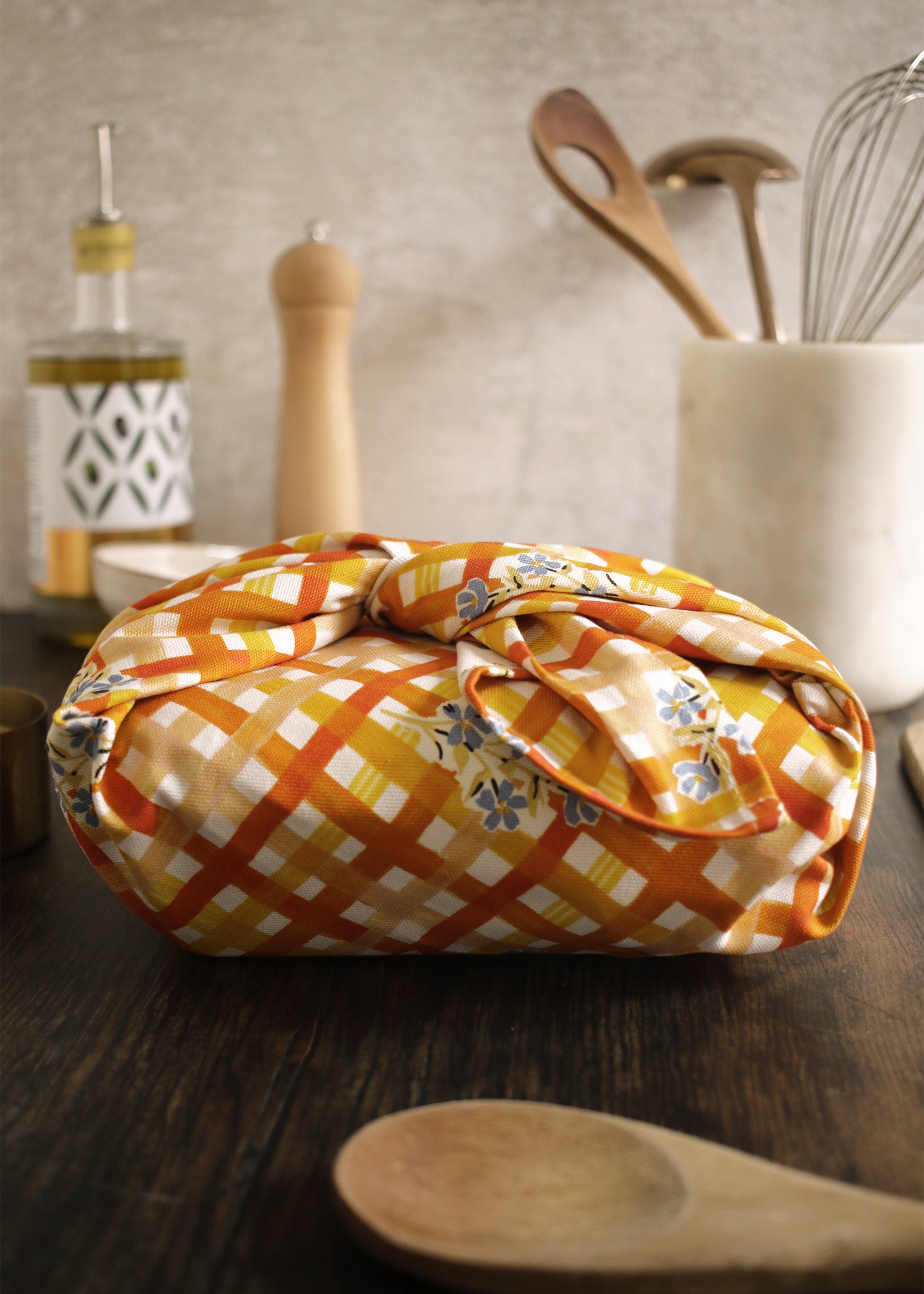 A gingham and floral tea towel, wrapped in a Furoshiki style