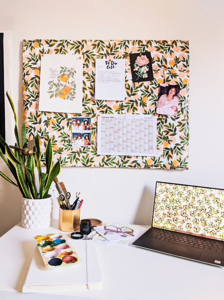 A light and airy home office space with a noticeboard decorated with peach wrapping paper 