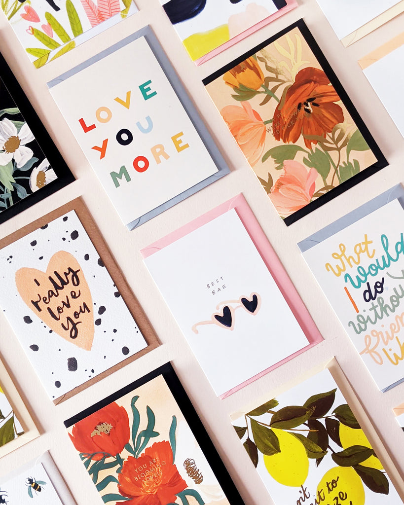 A collection of illustrated valentines cards with envelopes, laid flat on a pink background