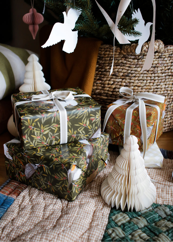 a pile of gifts wrapped in lovely bird pattered christmas paper, finished with grosgrain ribbons