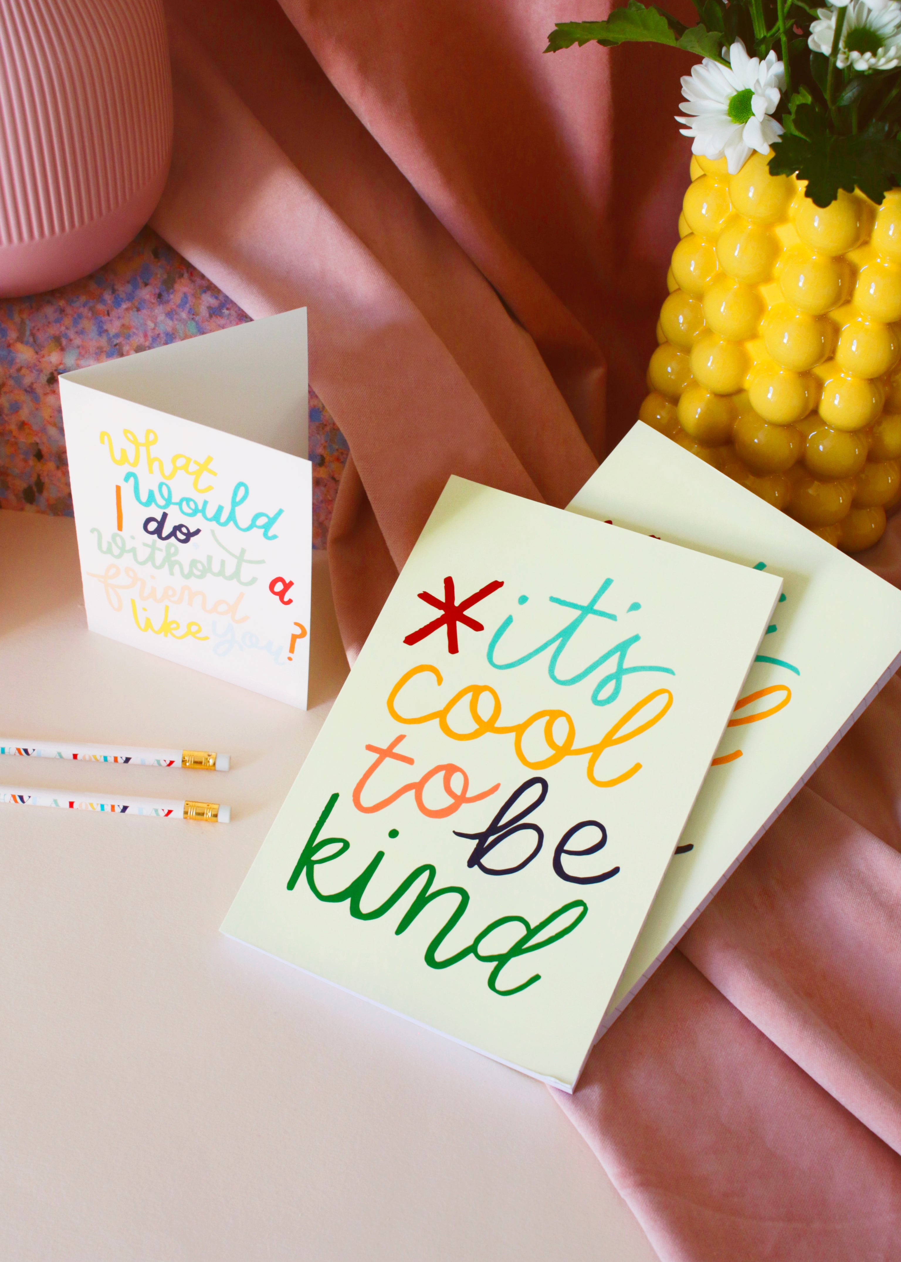 the It's cool to be kind notebook against some soft pink velvet