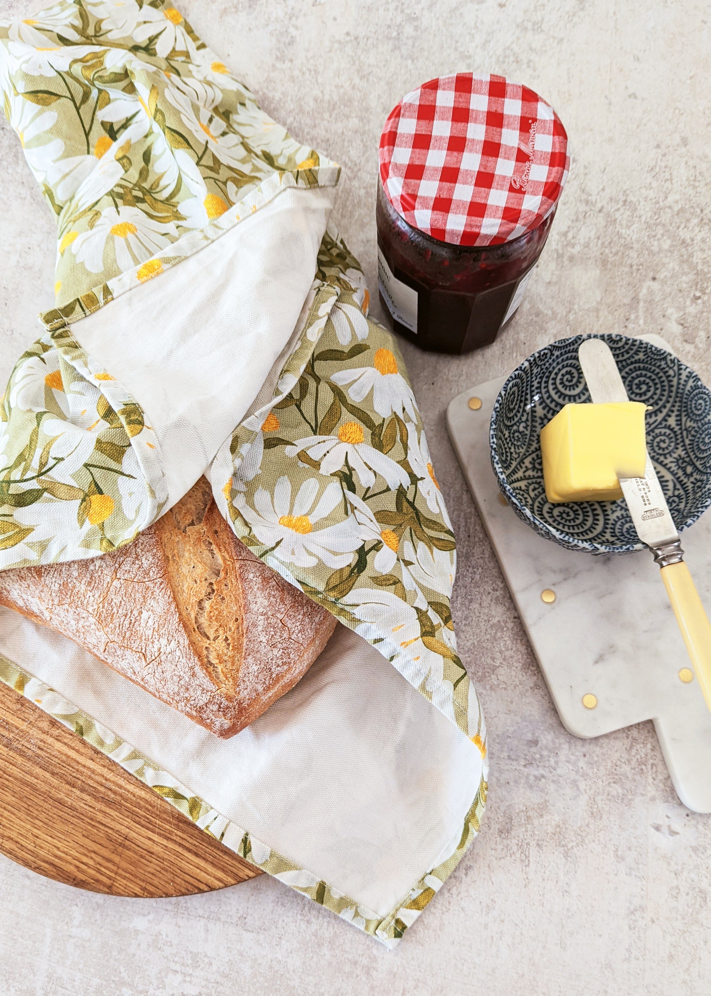 a freshly baked loaf of bread wrapped in a green, floral, cotton tea towel
