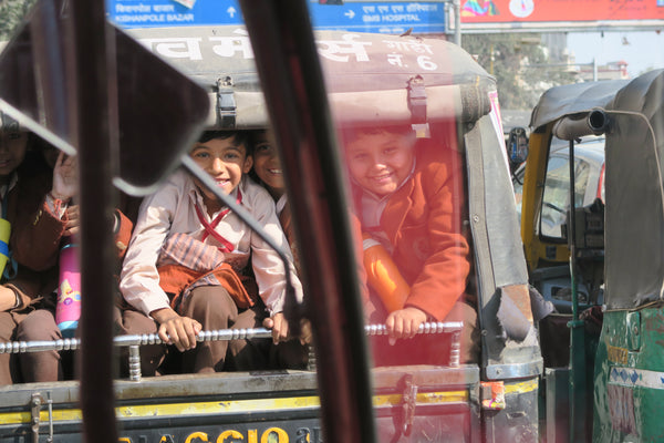 children smiling in a tuk tuk in jaipur