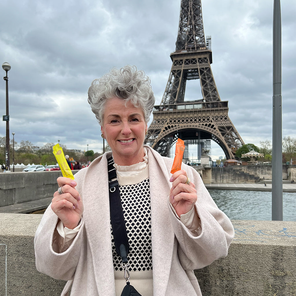 Image of Maxine in front of the Eiffel Tower holding AC Sachets