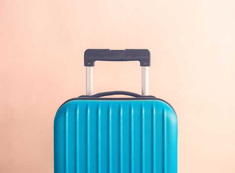 Blue suitcase on pink background. Book a getaway to beat Blue Monday & the January blues - Absolute Collagen