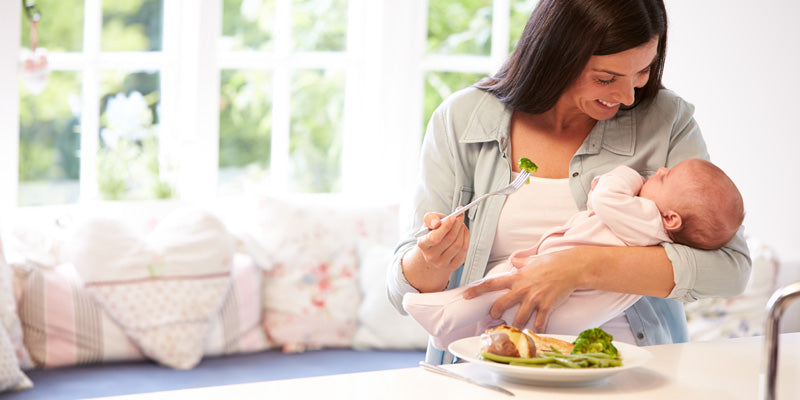 mother eating while holding baby