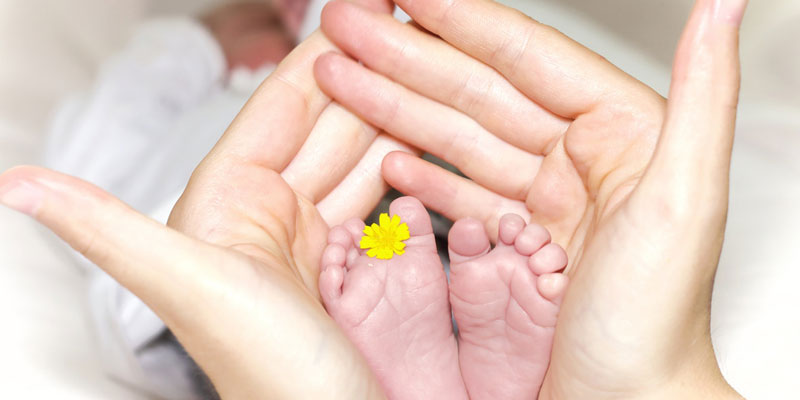 self care for new mums woman holding babies feet
