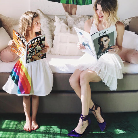 A mom and daughter smiling at each other while reading magazines