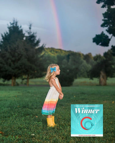 a girl wearing the classic rainbow dress with a rainbow in the background