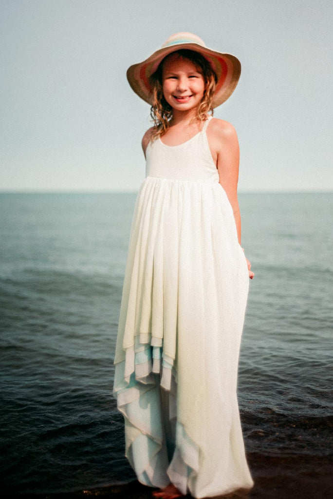child at the beach wearing the sea glass Stella. pleiades designs and the traveling dress collective