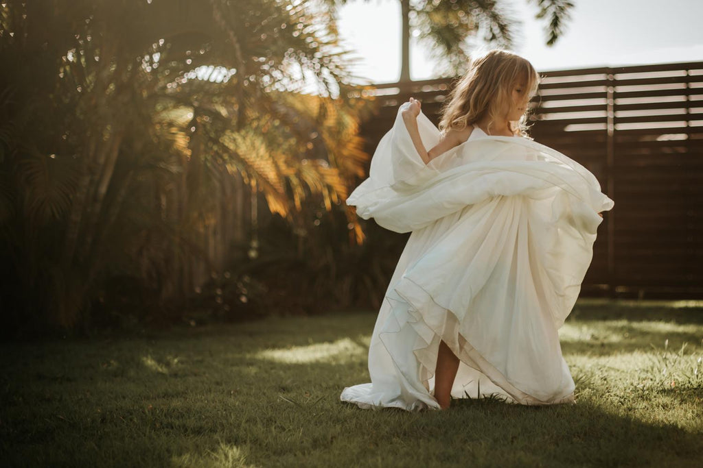 a child dancing at dawn wearing the sea glass Stella dress. Pleaides Designs and the traveling dress collective