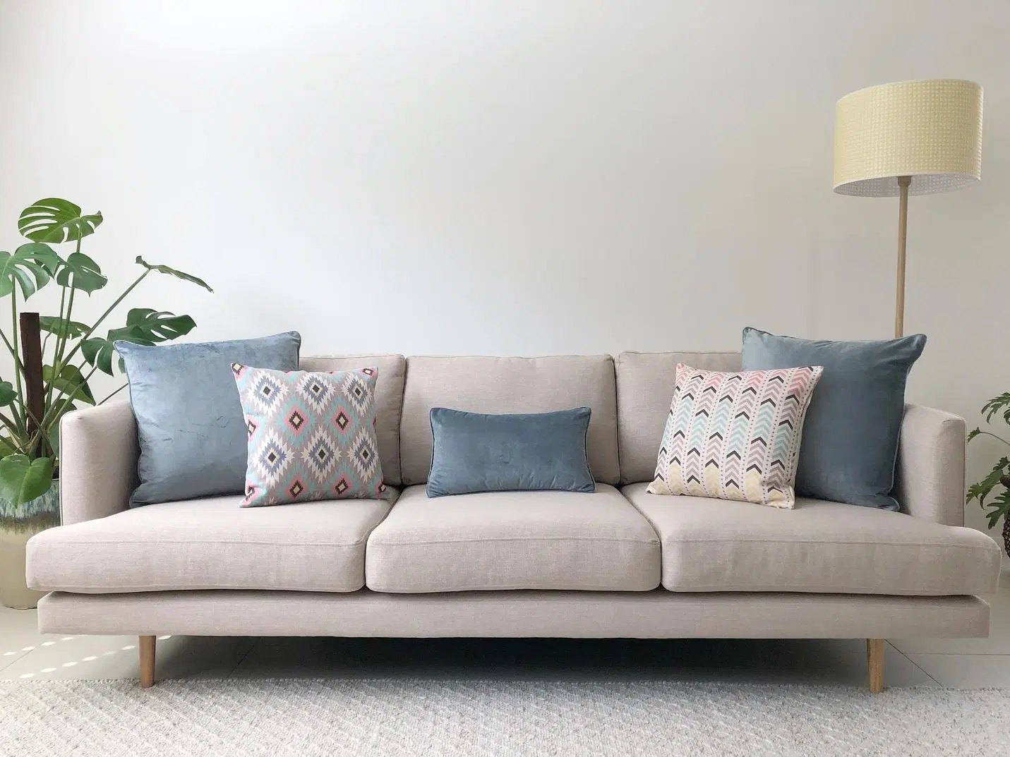 A beige sofa with five decorative cushions in various shades and patterns