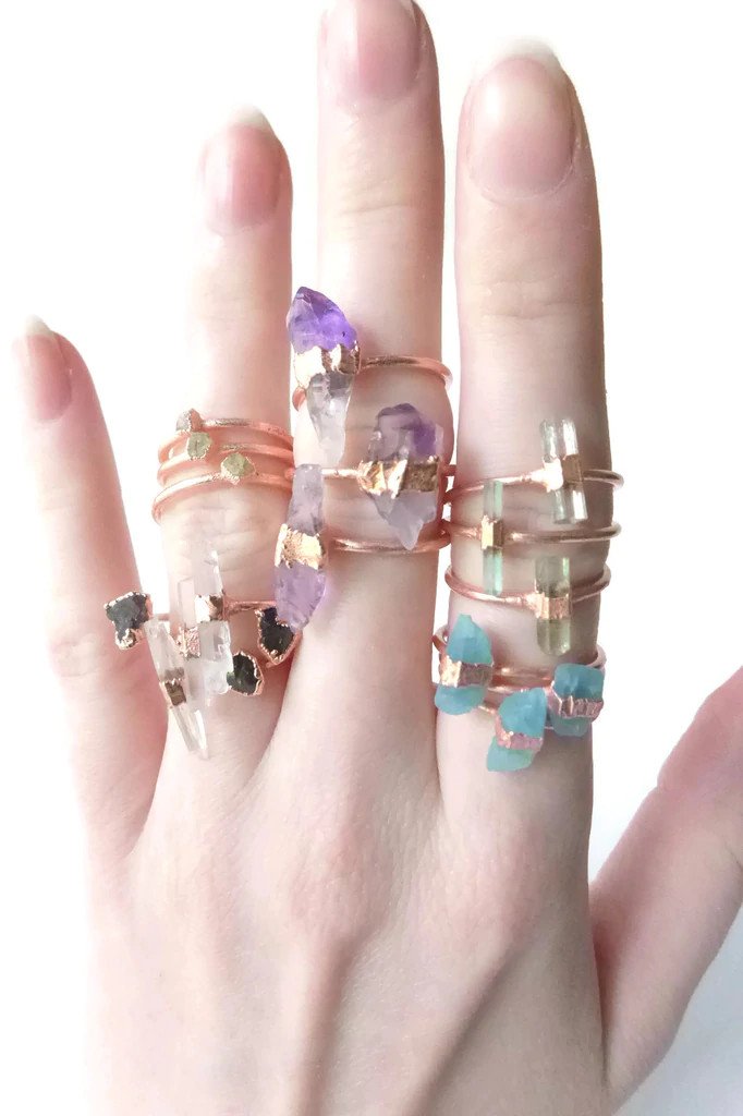 A model wearing a lot of copper gemstone rings.