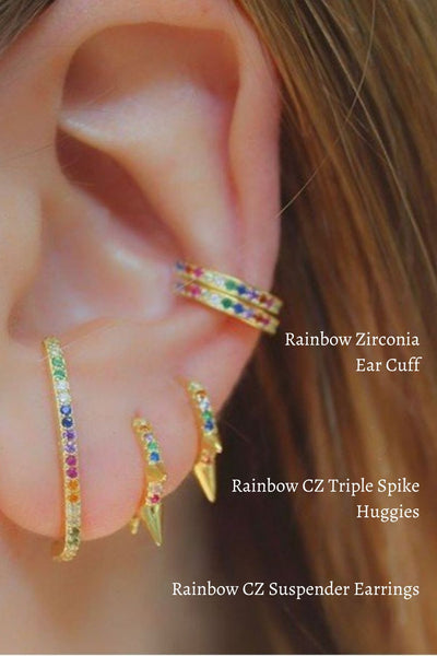 A woman wearing gold earrings with rainbow zirconia stones.