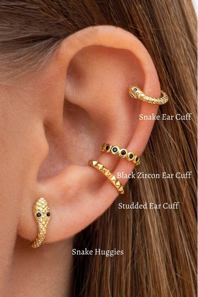 A woman wearing multiple gold snake earrings.