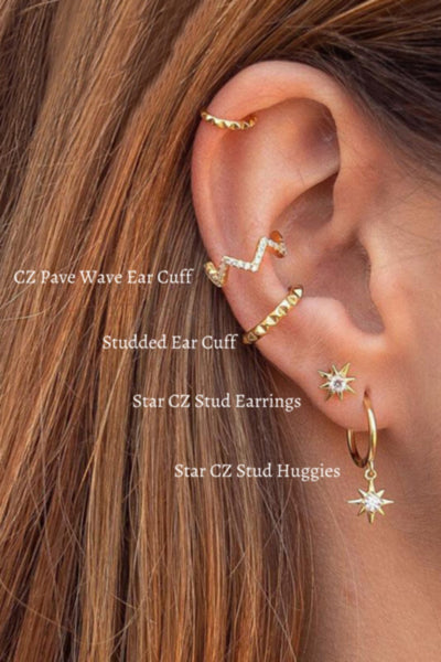 A woman wearing multiple gold CZ star earrings.